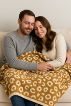 Load image into Gallery viewer, Man and woman sitting on a couch under a leopard print blanket, smiling.