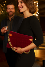 Load image into Gallery viewer, Woman holding a red clutch with gold chain in a social setting