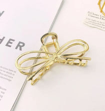 Load image into Gallery viewer, Two hair claw clips, one in gold and one in silver color, with a bowknot design, displayed on a white background with a magazine-like texture.