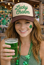Load image into Gallery viewer, Woman wearing a 'Lucky Charm' cap, holding a green drink, with a shamrock on her cheek, in a festive setting.