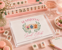 Load image into Gallery viewer, Mahjong set with decorative tiles and 'Mahjong Social Club' packaging on a pink surface.
