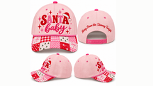 Load image into Gallery viewer, A pink Christmas-themed baseball cap shown from multiple angles on a white background. The front view features 'SANTA baby' in red and white lettering with a pink Santa hat graphic and a red-and-white gingham brim.
